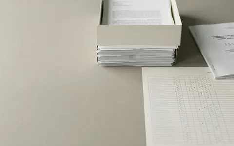 A test bench for text: printed documents boxed and stacked, a ruled score sheet with a blue pencil beside them, and a stamped test report.