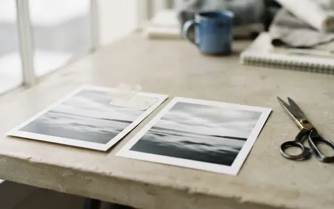 Two copies of a printed photograph, one with a small label on its corner and one where only a faint mark remains.